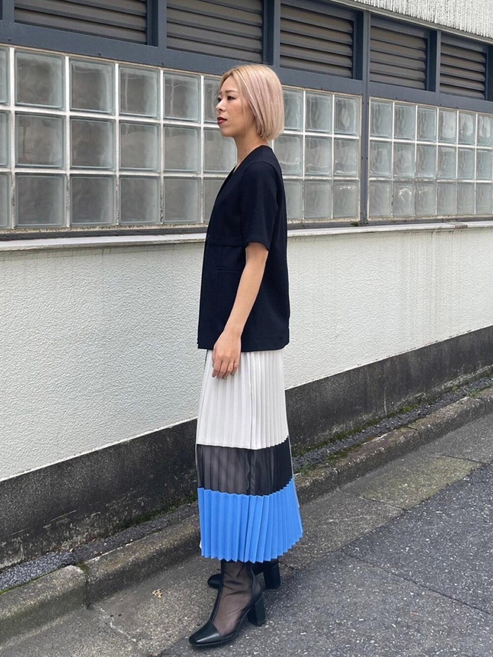 ブラック系のノーカラージャケット、ブルー系のスカートを着用したレディースの春コーディネートの2枚目の写真