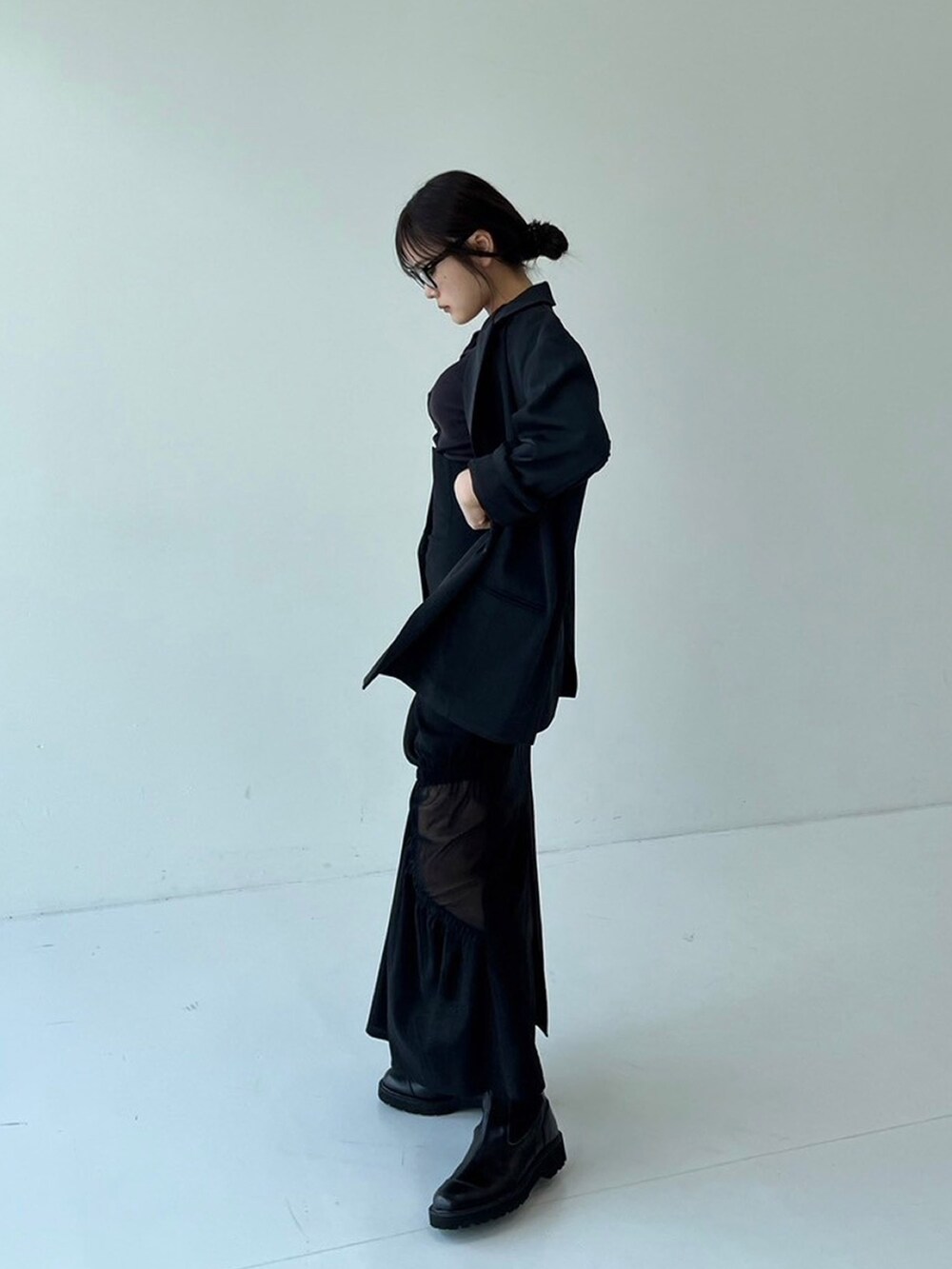 ブラック系のスカート、ブラック系のテーラードジャケット、ブラウン系のTシャツ/カットソーを着用したレディースの秋コーディネートの2枚目の写真