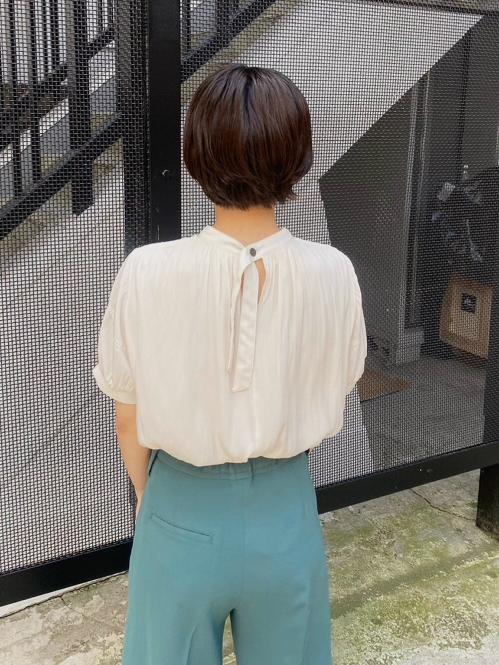 ベージュ系のシャツ/ブラウス、グリーン系のスラックスを着用したレディースの春コーディネートの3枚目の写真