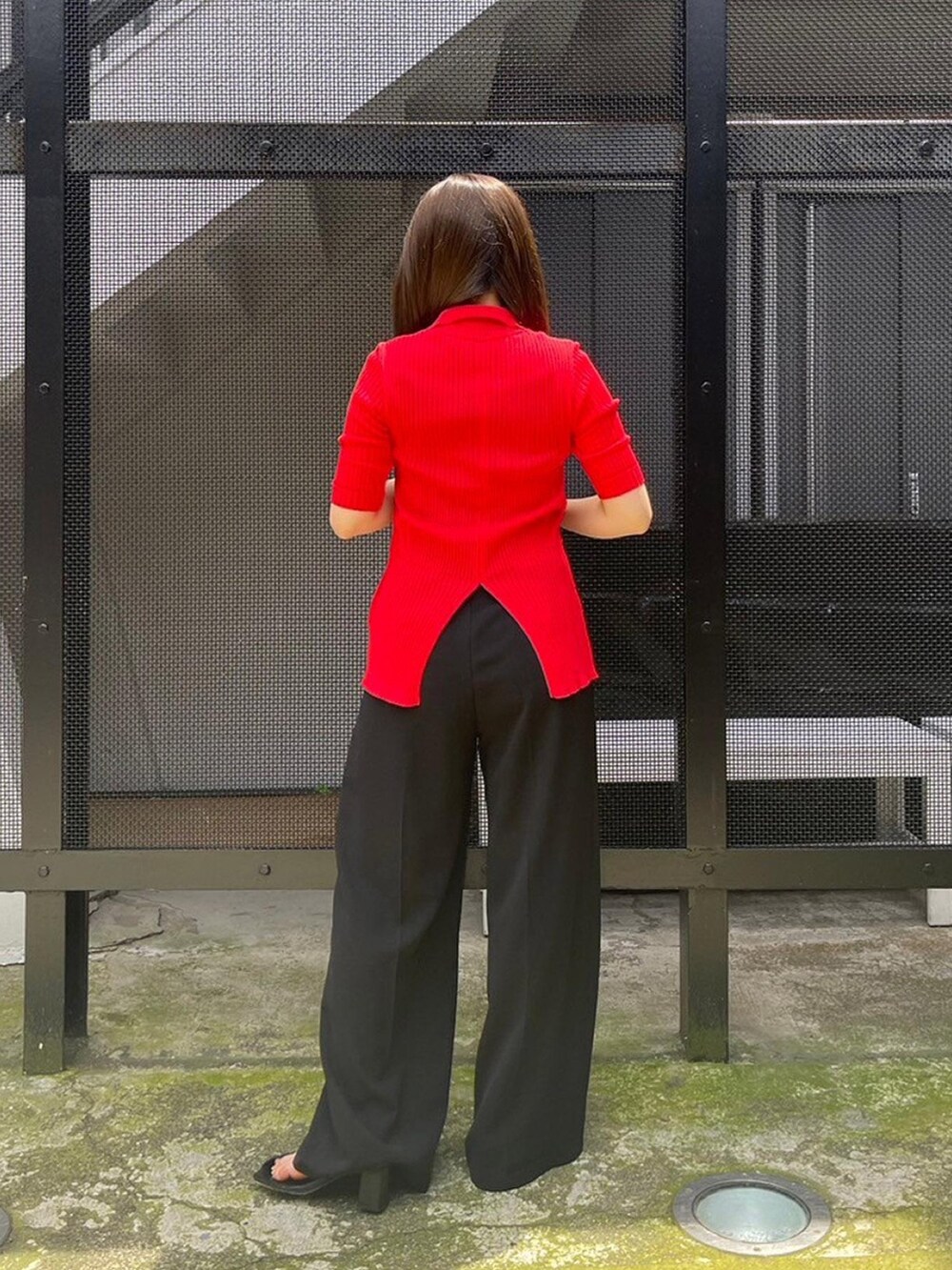 ブラック系のスラックス、レッド系のニット/セーターを着用したレディースの春コーディネートの3枚目の写真