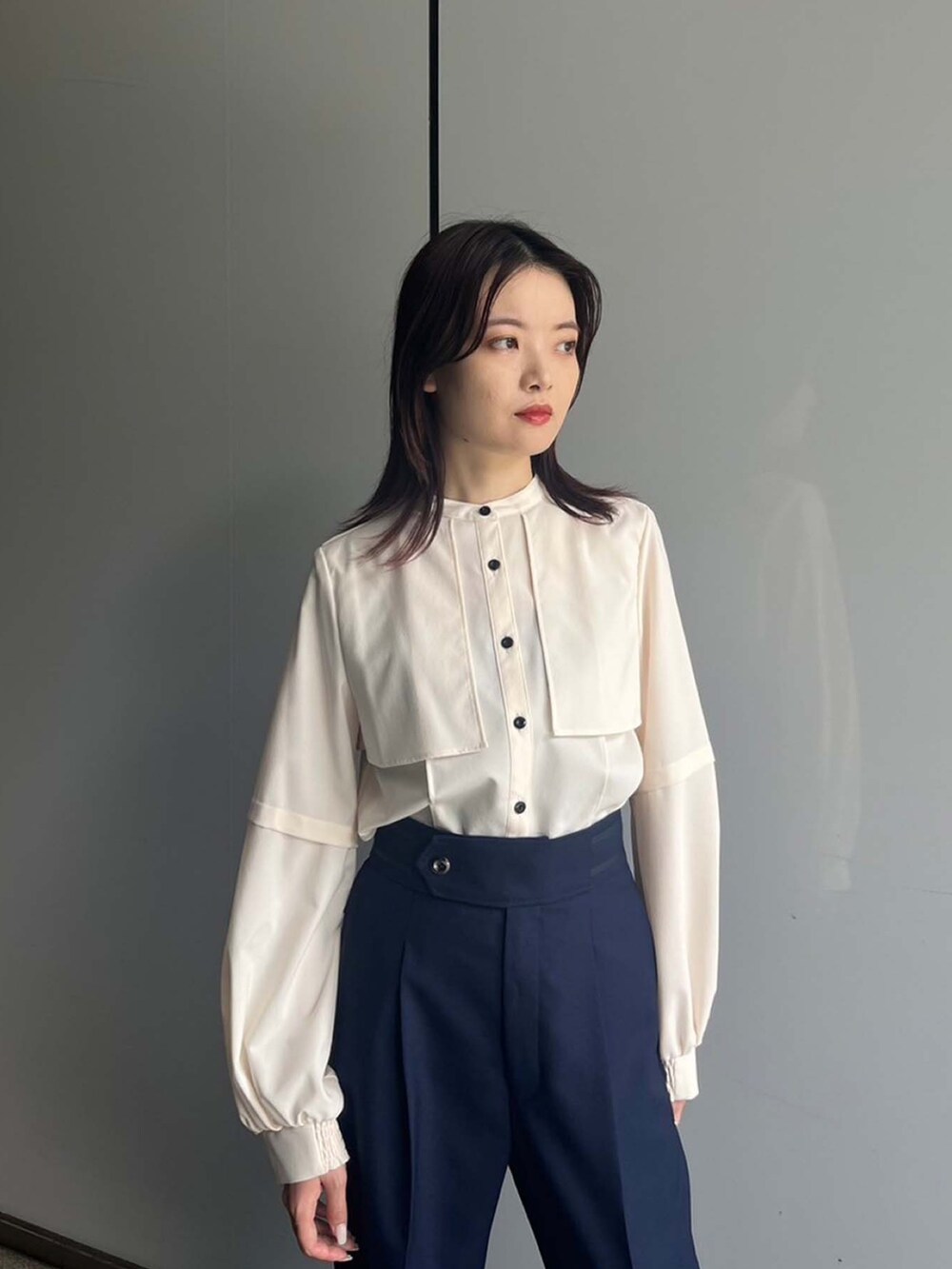 ベージュ系のシャツ/ブラウス、ブルー系のスラックスを着用したレディースの夏コーディネートの3枚目の写真