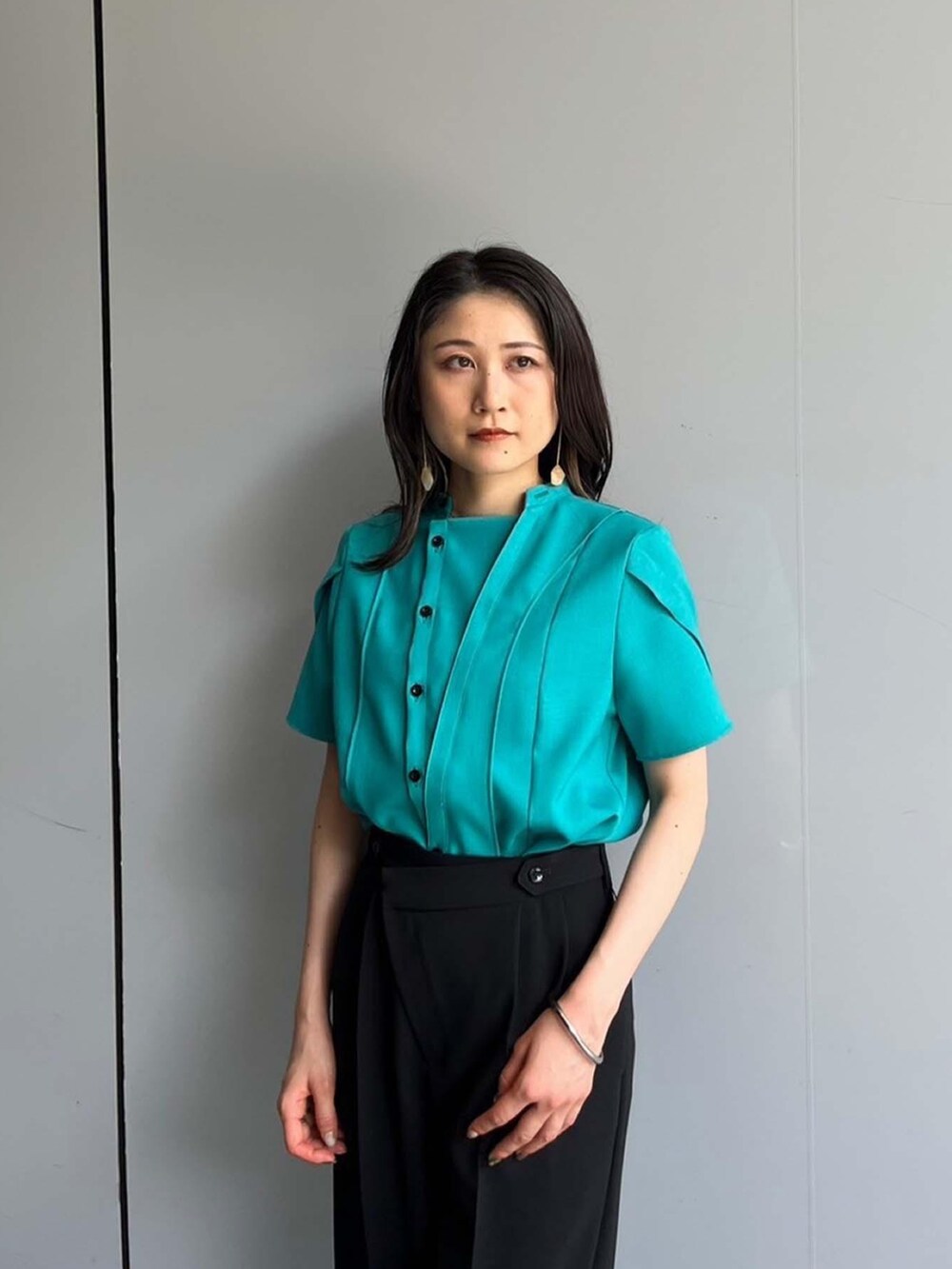 グリーン系のシャツ/ブラウス、ブラック系のスラックスを着用したレディースの夏コーディネートの3枚目の写真