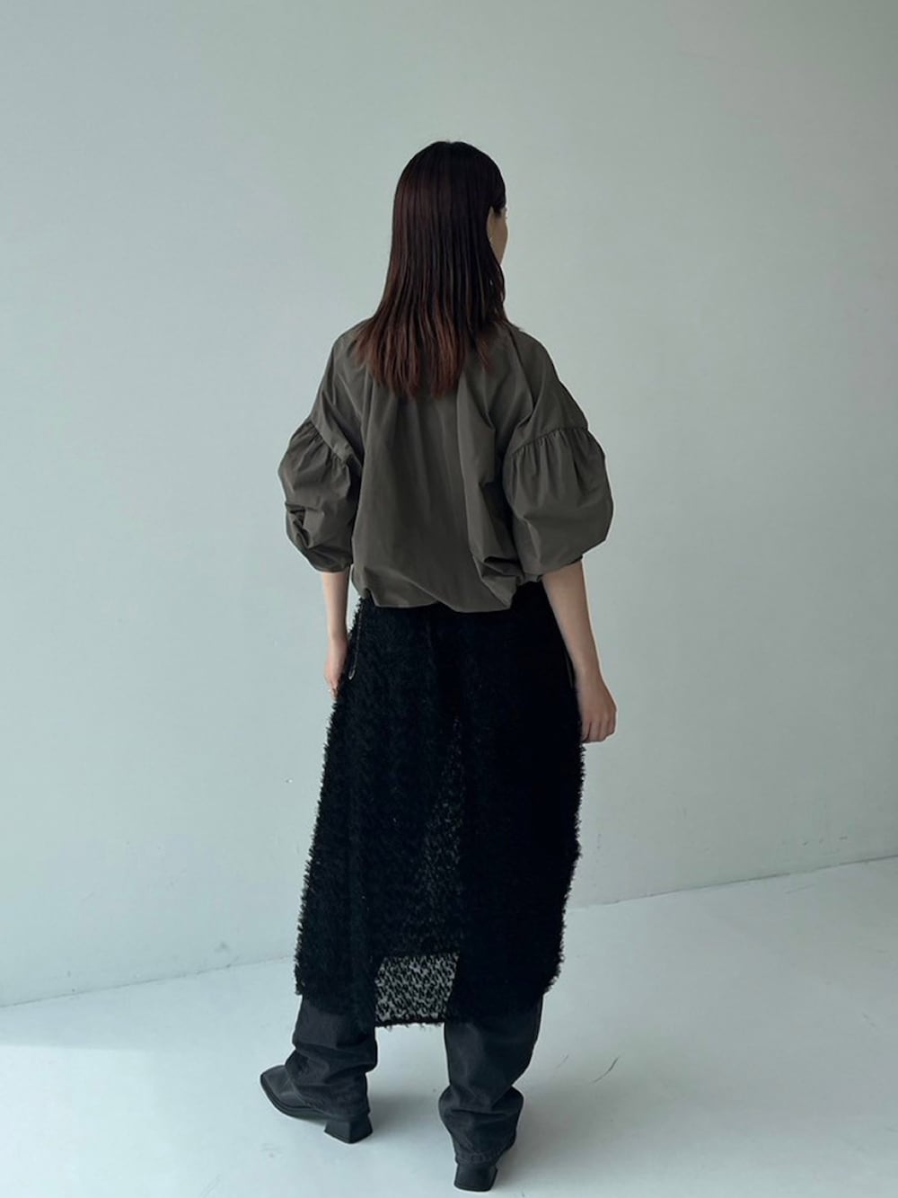 ブラウン系のブルゾン、ブラック系のスカートを着用したレディースの秋コーディネートの3枚目の写真