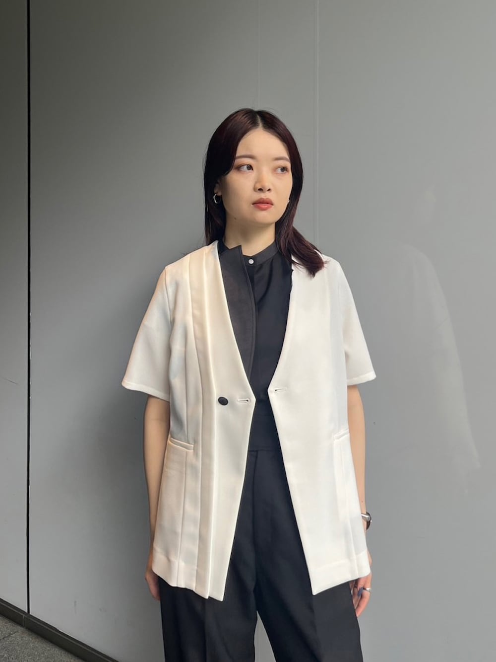 ブラック系のシャツ/ブラウス、ホワイト系のノーカラージャケット、ブラック系のスラックスを着用したレディースの夏コーディネートの3枚目の写真