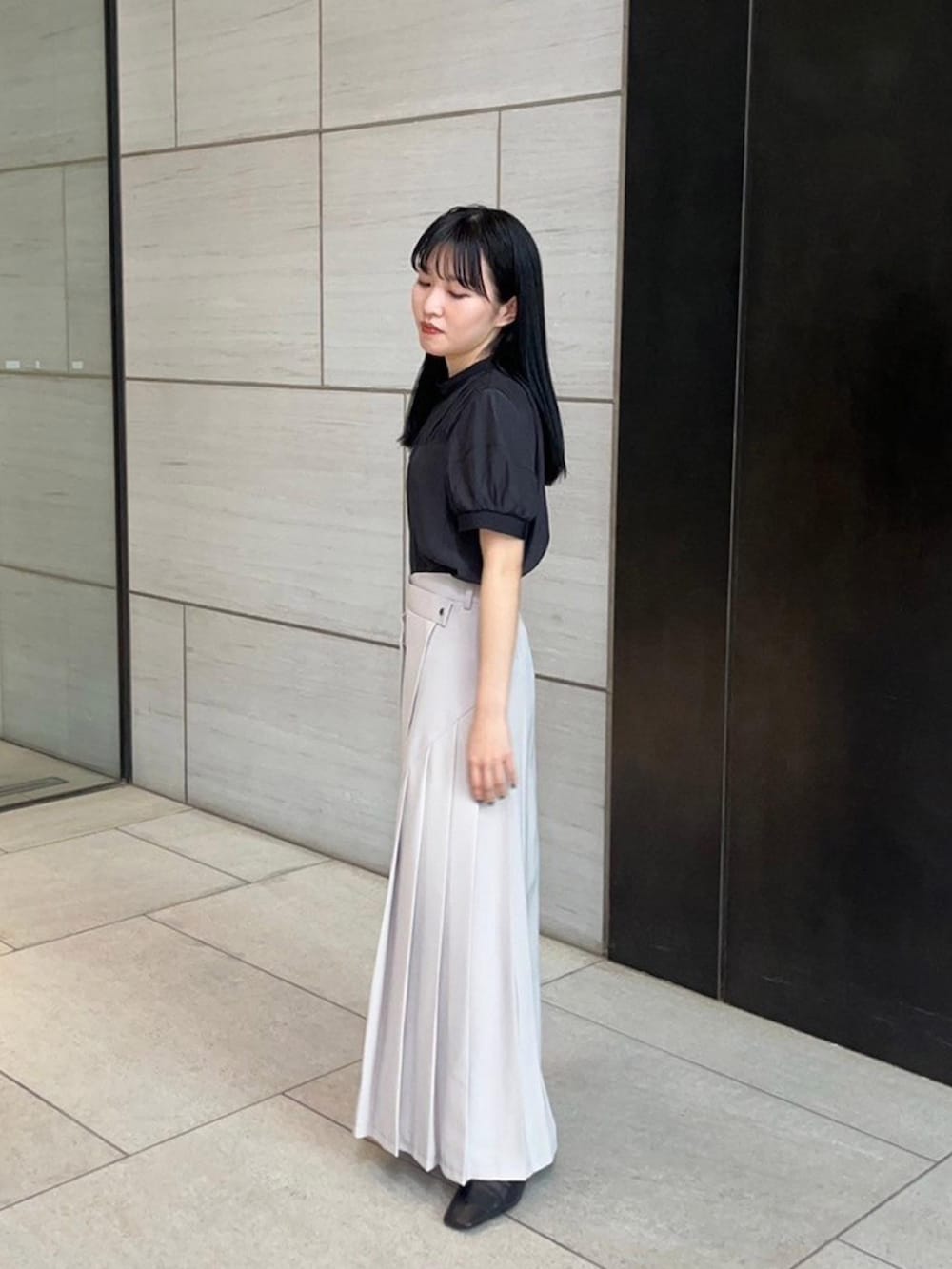 ベージュ系のスカート、ブラック系のシャツ/ブラウスを着用したレディースの春コーディネートの2枚目の写真