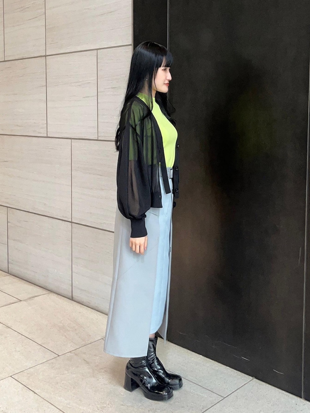 グレー系のスカート、ブラック系のカーディガン/ボレロ、グリーン系のニット/セーターを着用したレディースの春コーディネートの4枚目の写真