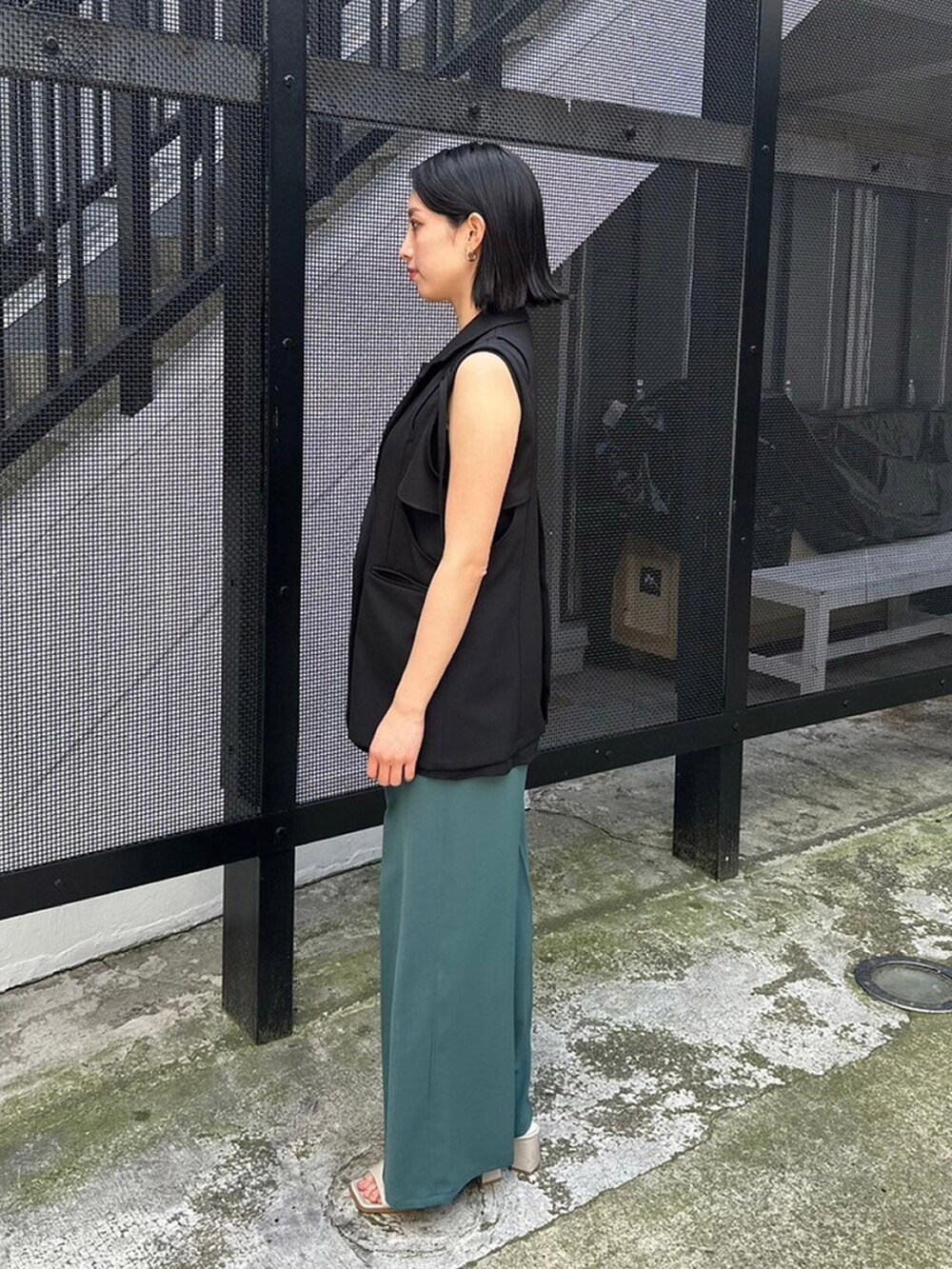 ブラック系のベスト、グリーン系のスラックスを着用したレディースの春コーディネートの2枚目の写真