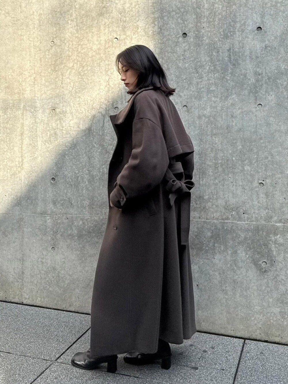 ブラウン系のステンカラーコートを着用したレディースの秋コーディネートの2枚目の写真