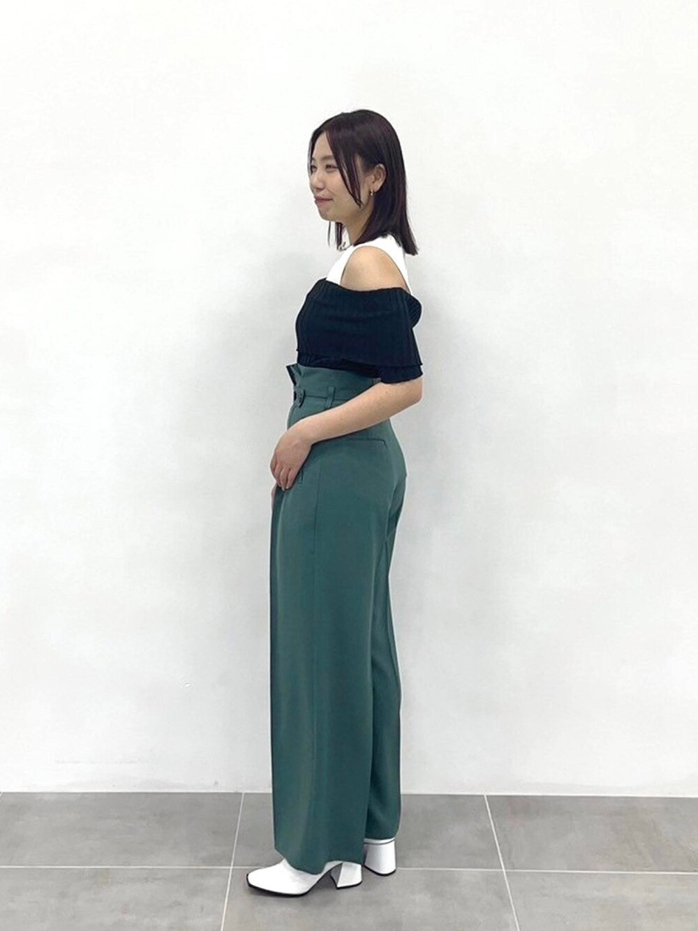 グリーン系のスラックス、ブラック系のニット/セーターを着用したレディースの春コーディネートの2枚目の写真