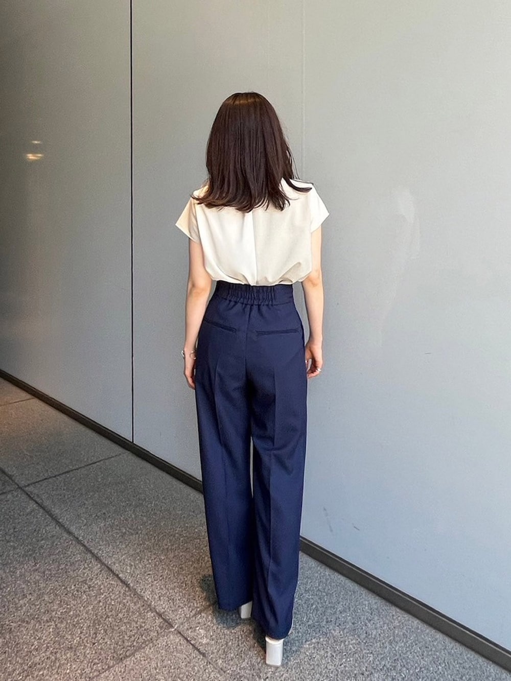 ベージュ系のシャツ/ブラウス、ブルー系のスラックスを着用したレディースの夏コーディネートの3枚目の写真