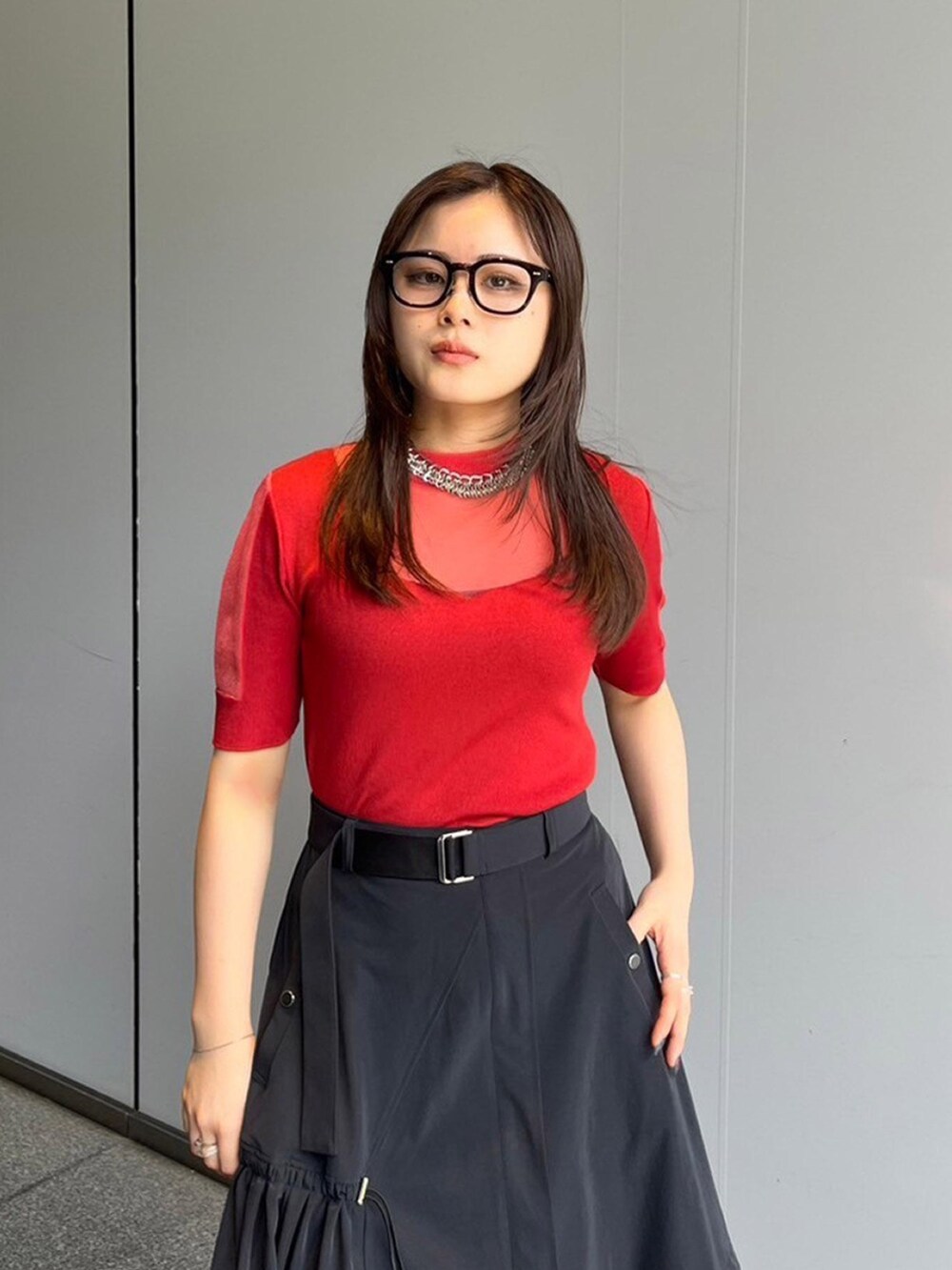 レッド系のニット/セーター、ブラック系のスカートを着用したレディースの夏コーディネートの4枚目の写真