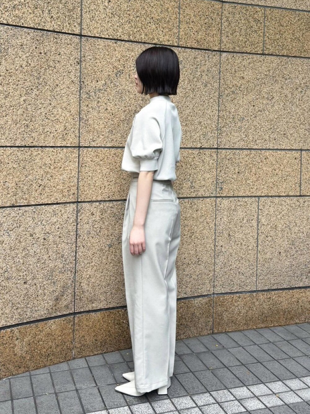 ベージュ系のニット/セーター、ベージュ系のスラックスを着用したレディースの春コーディネートの2枚目の写真