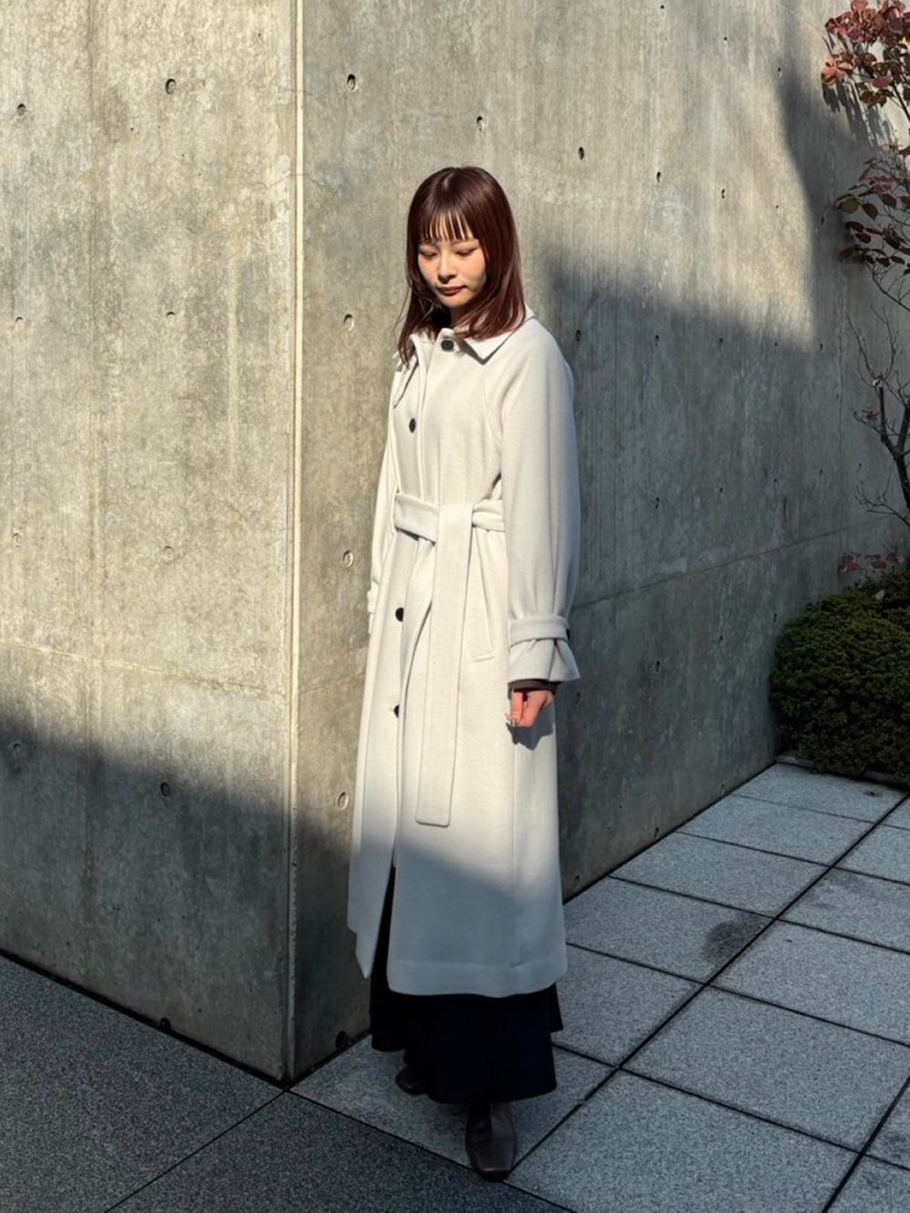 ホワイト系のステンカラーコートを着用したレディースの秋コーディネートの3枚目の写真