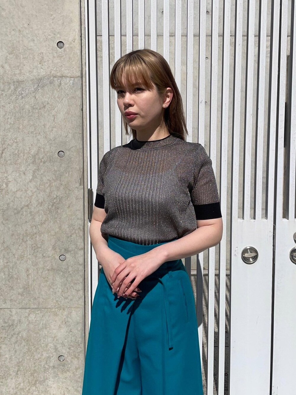 ゴールド系のニット/セーター、グリーン系のスラックスを着用したレディースの春コーディネートの5枚目の写真