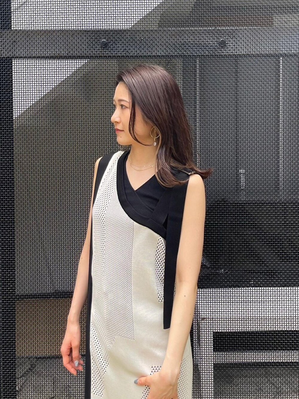 ホワイト系のワンピース、ブラック系のタンクトップ、ブラック系のデニムパンツを着用したレディースの春コーディネートの5枚目の写真