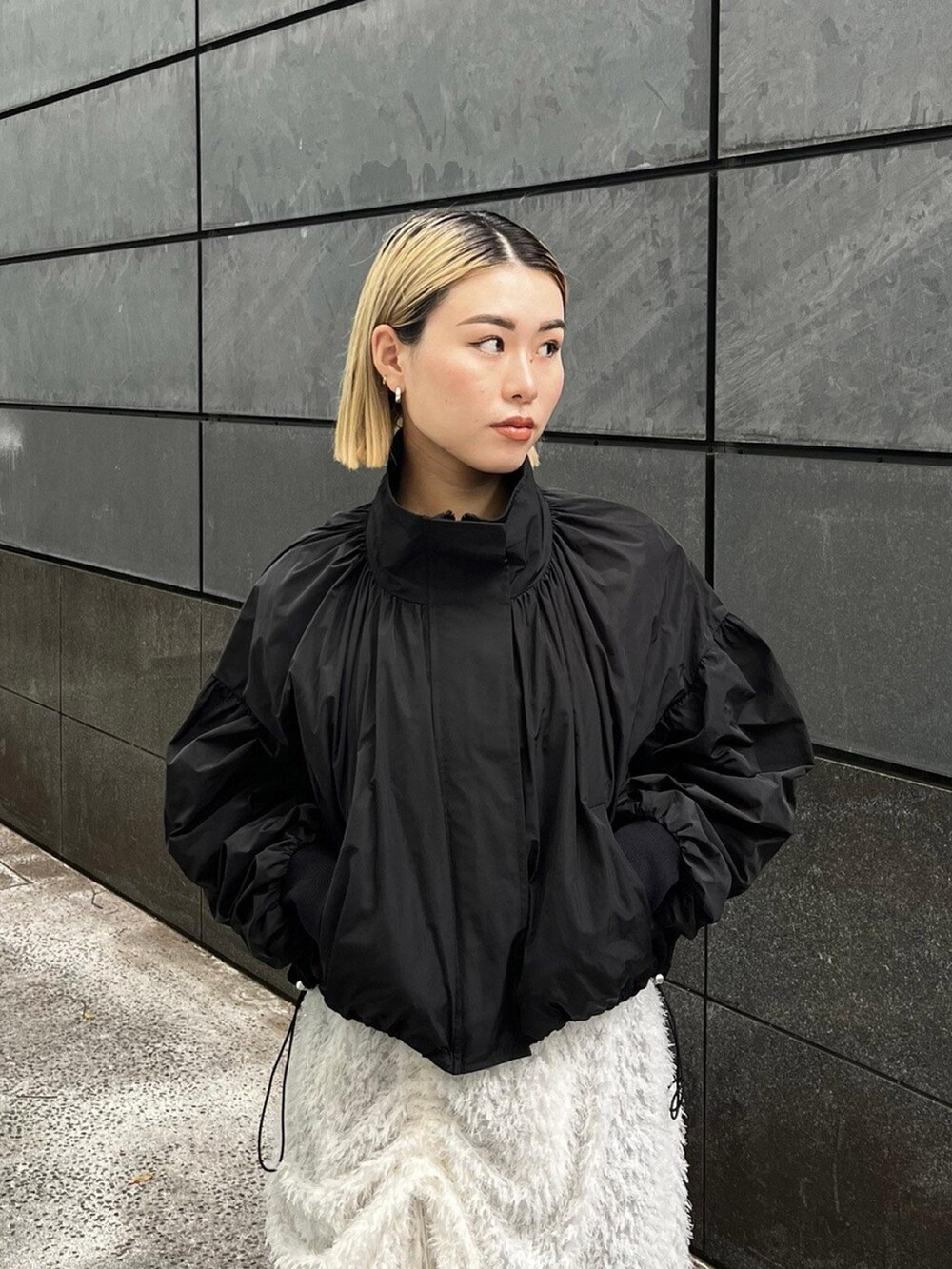 ブラック系のブルゾン、ホワイト系のスカートを着用したレディースの秋コーディネートの4枚目の写真