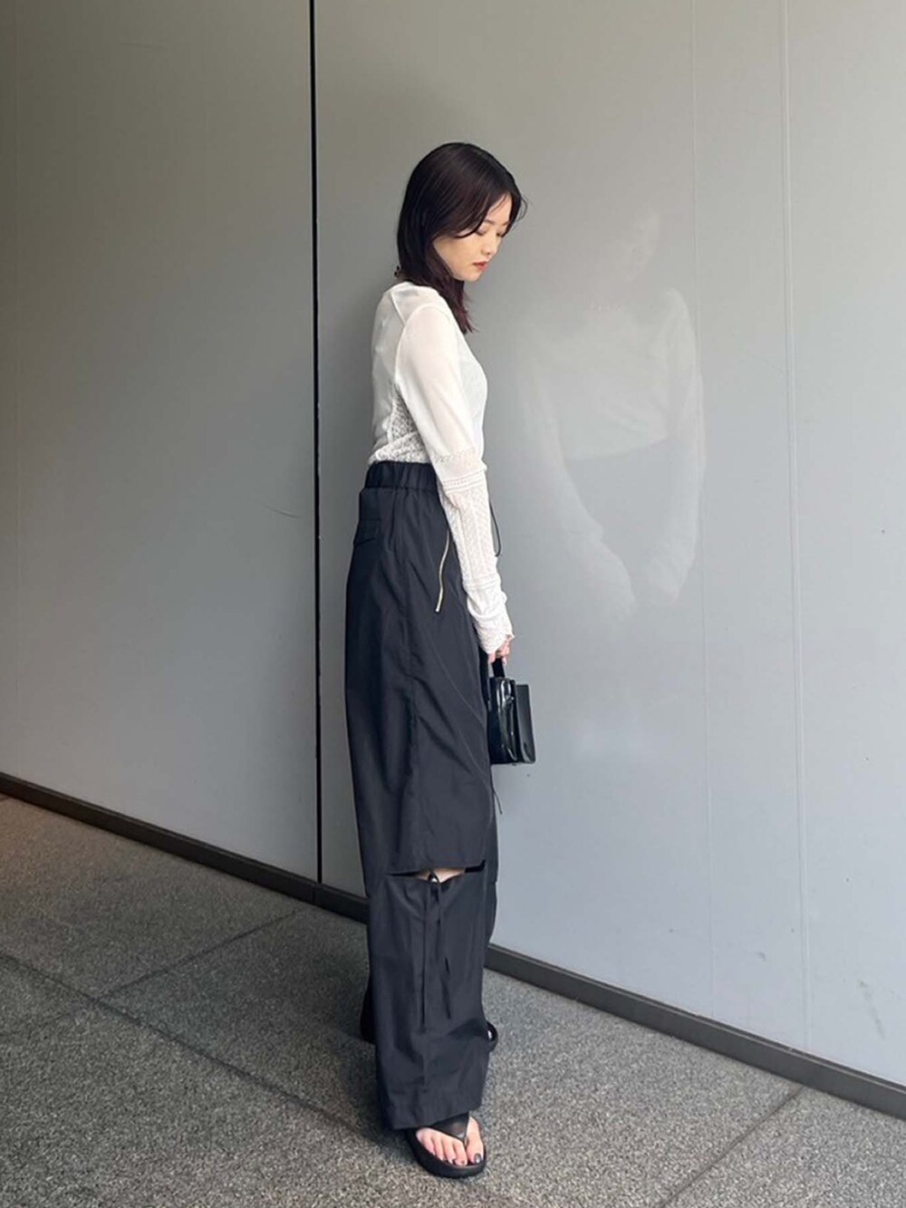 ホワイト系のニット/セーター、ブラック系のその他パンツを着用したレディースの夏コーディネートの2枚目の写真