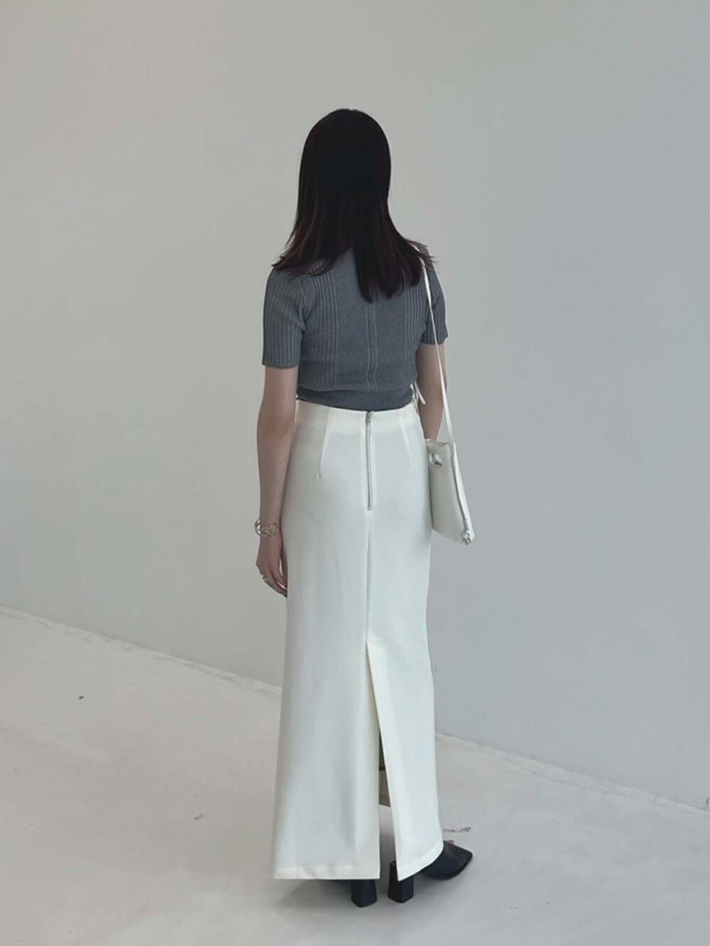 グレー系のポロシャツ、ホワイト系のスカートを着用したレディースの夏コーディネートの3枚目の写真