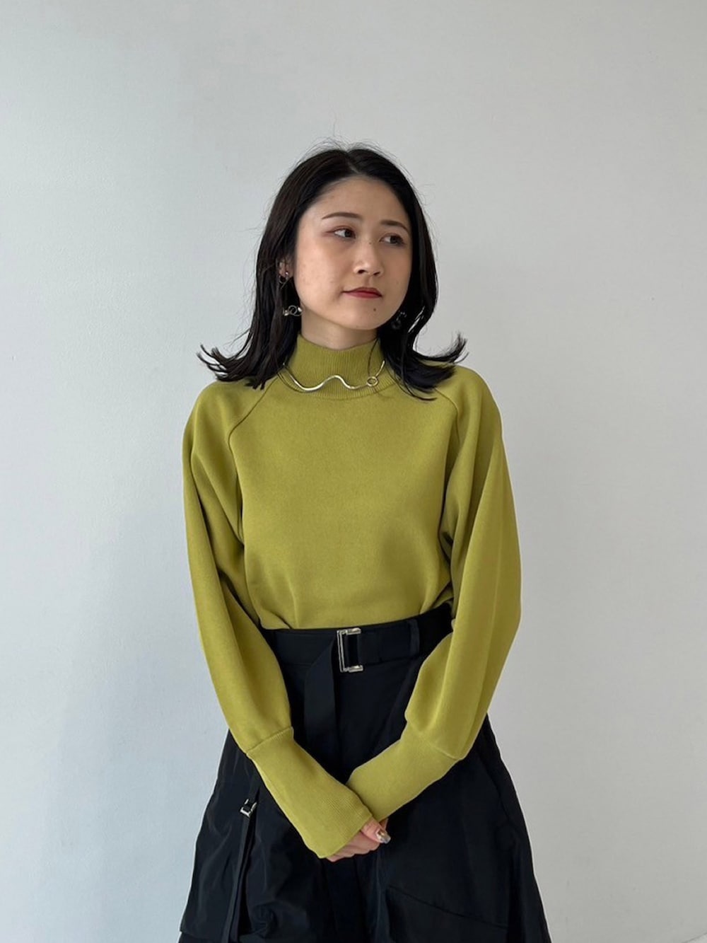 ブラック系のスカート、イエロー系のニット/セーターを着用したレディースの秋コーディネートの3枚目の写真