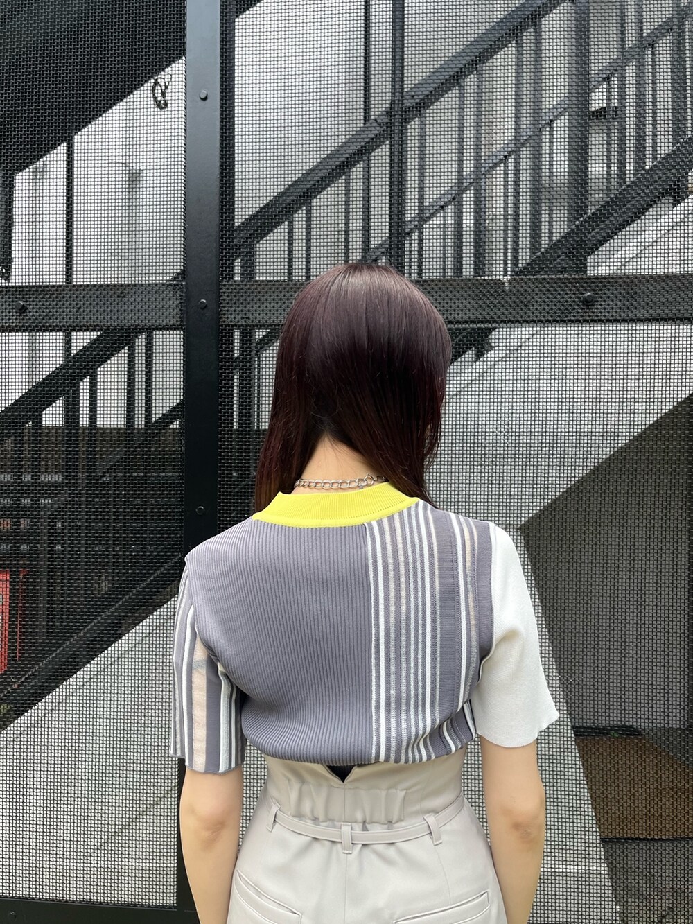 イエロー系のニット/セーター、グレー系のスラックスを着用したレディースの春コーディネートの6枚目の写真