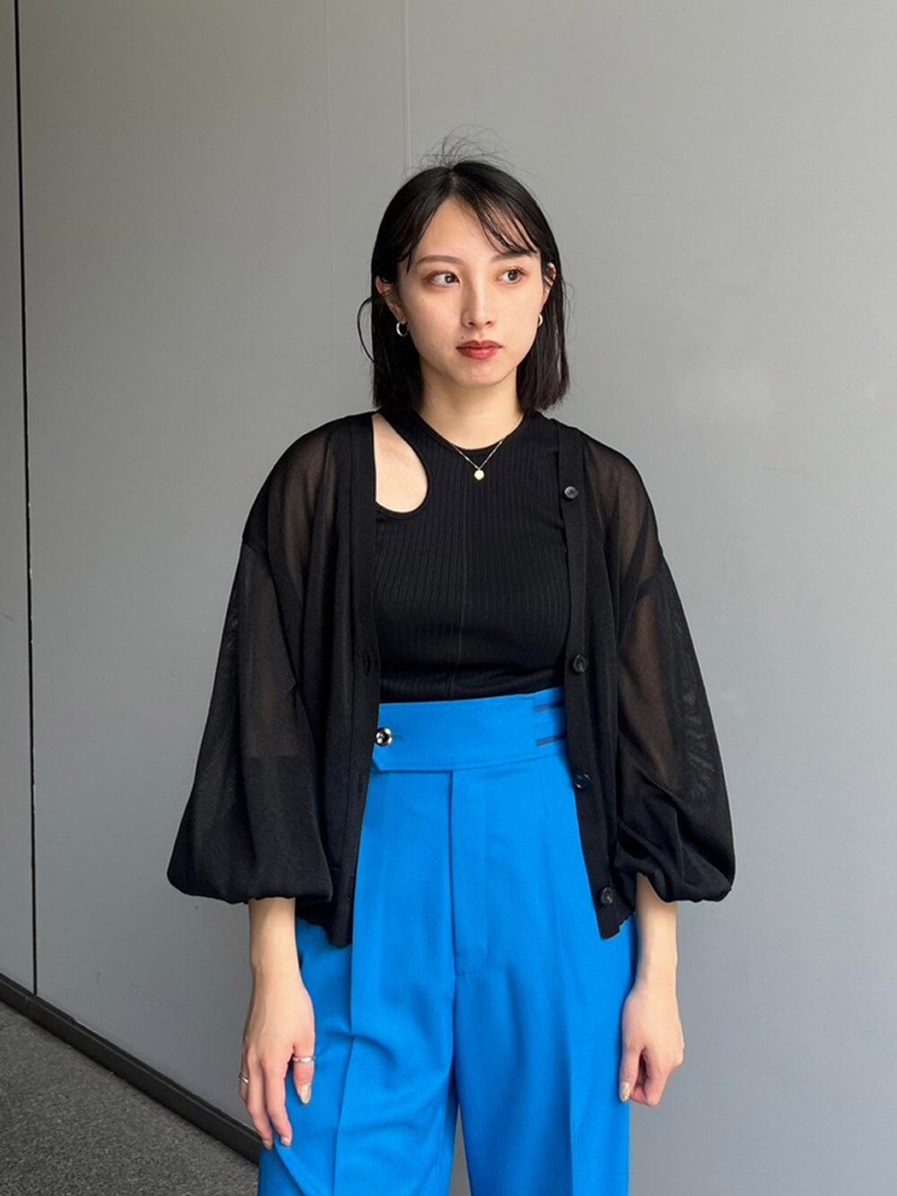 ブラック系のタンクトップ、ブラック系のカーディガン/ボレロ、ブルー系のスラックスを着用したレディースの夏コーディネートの4枚目の写真