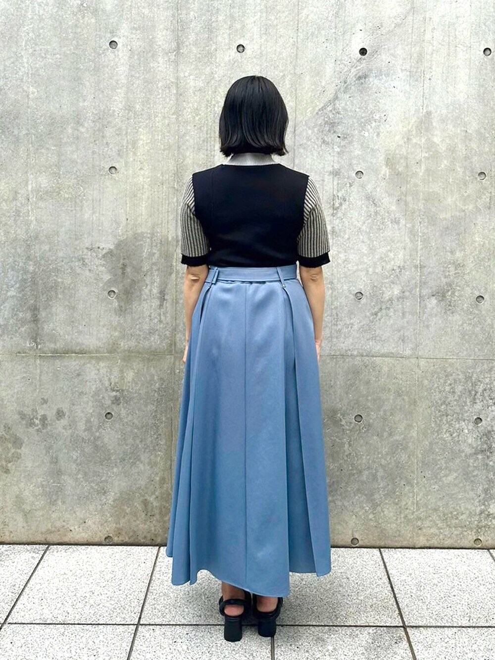 ブラック系のニット/セーター、ブルー系のスカートを着用したレディースの春コーディネートの3枚目の写真