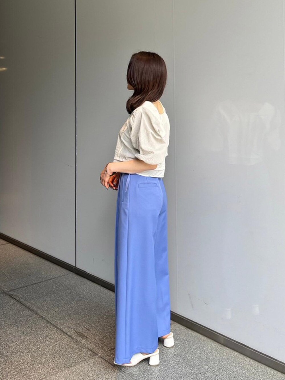 ホワイト系のシャツ/ブラウス、ブルー系のスラックスを着用したレディースの夏コーディネートの2枚目の写真