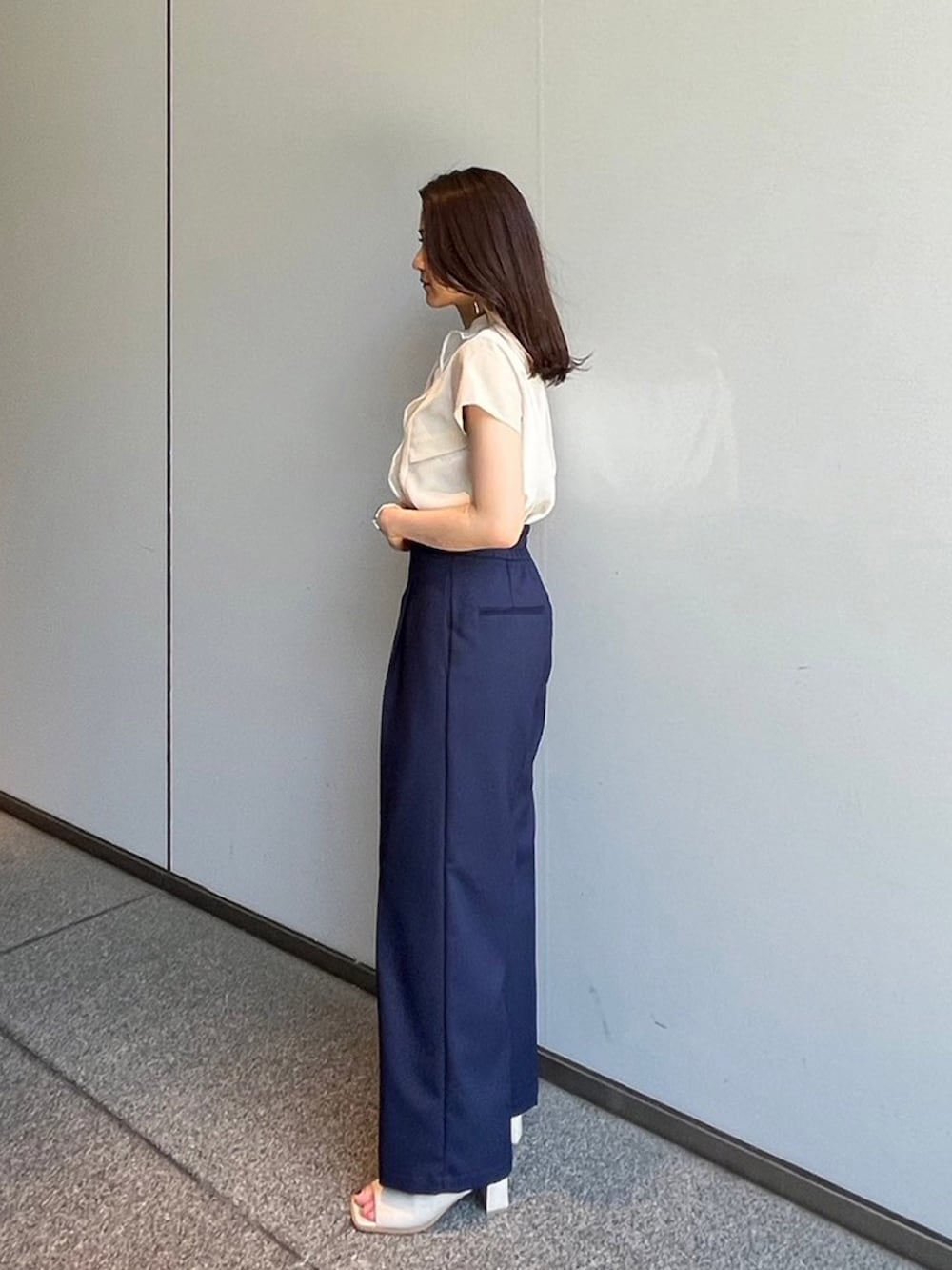 ベージュ系のシャツ/ブラウス、ブルー系のスラックスを着用したレディースの夏コーディネートの2枚目の写真