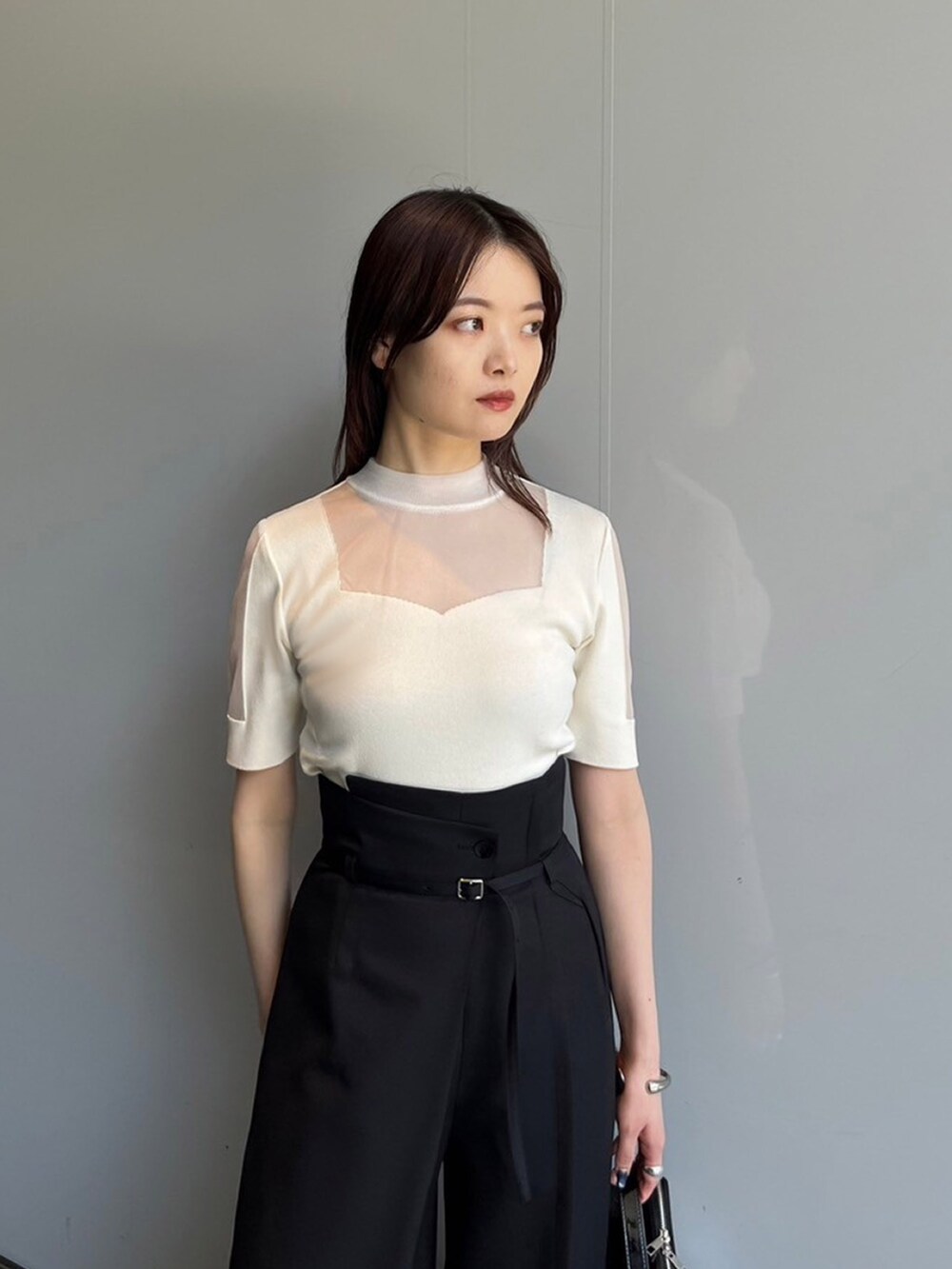 ホワイト系のニット/セーター、ブラック系のスラックスを着用したレディースの夏コーディネートの3枚目の写真