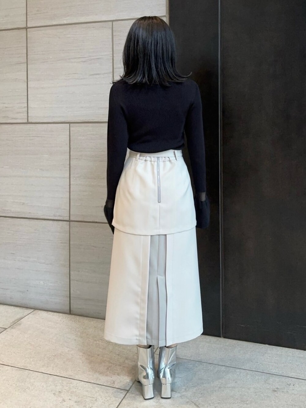 ベージュ系のスカート、ブラック系のニット/セーターを着用したレディースの春コーディネートの3枚目の写真