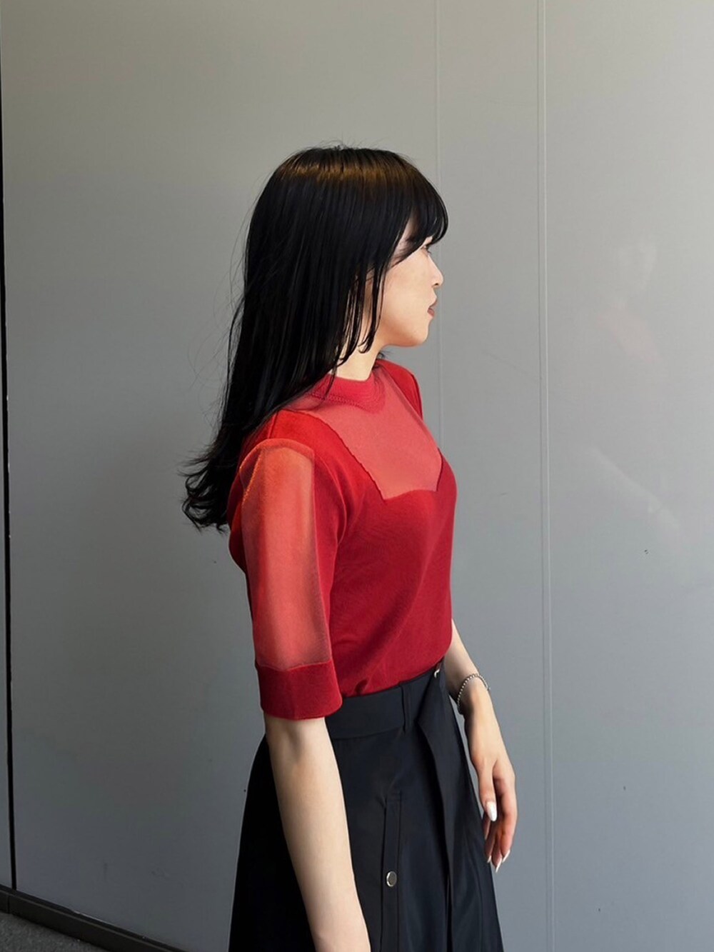 レッド系のニット/セーター、ブラック系のスカートを着用したレディースの夏コーディネートの3枚目の写真