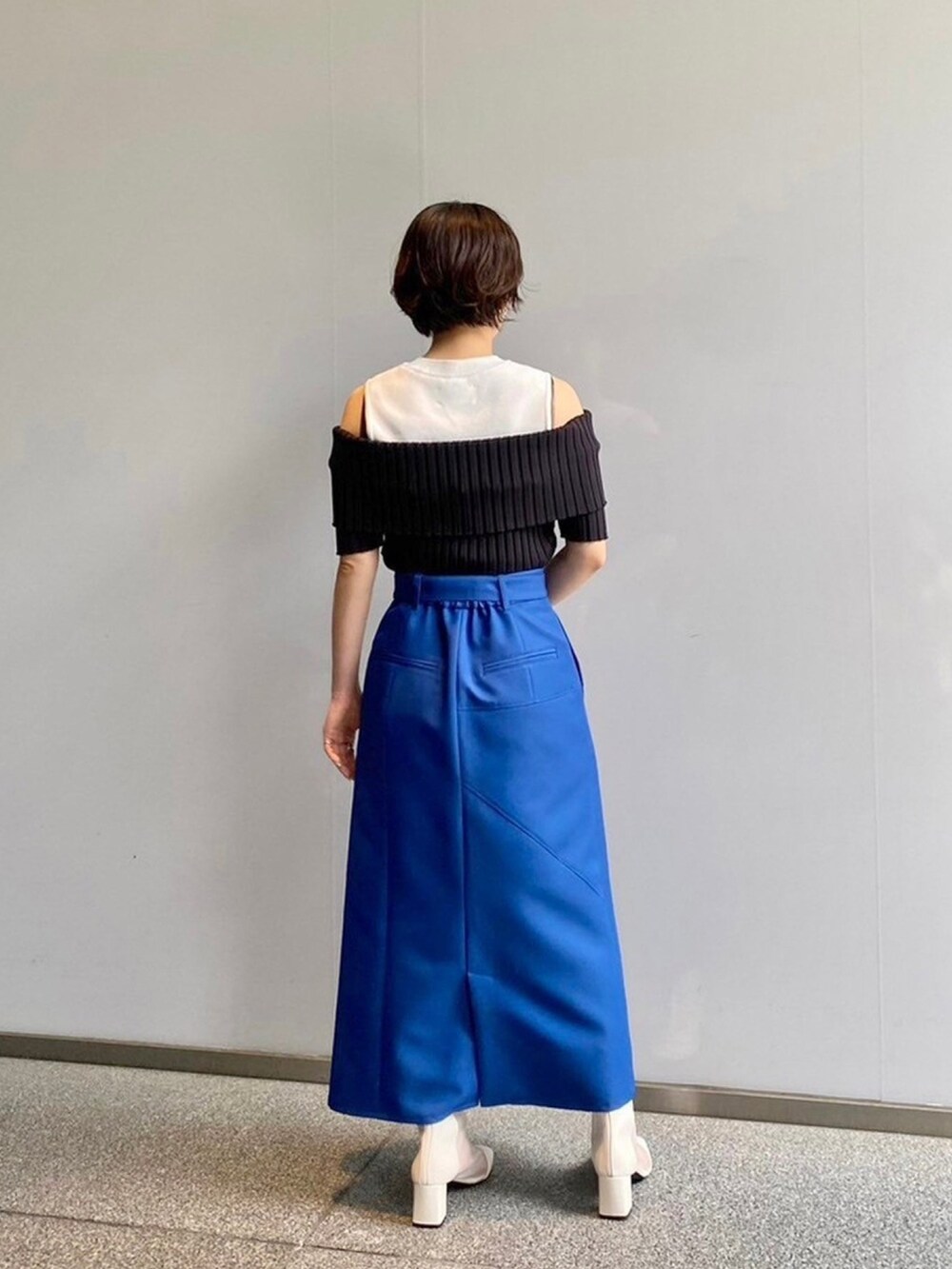 ブラック系のニット/セーター、ブルー系のスカートを着用したレディースの春コーディネートの3枚目の写真