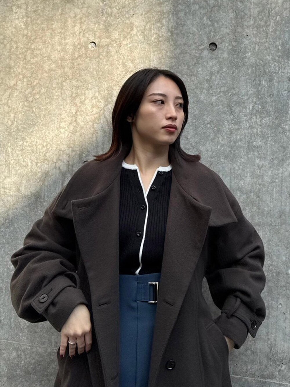 ブラウン系のステンカラーコートを着用したレディースの秋コーディネートの4枚目の写真