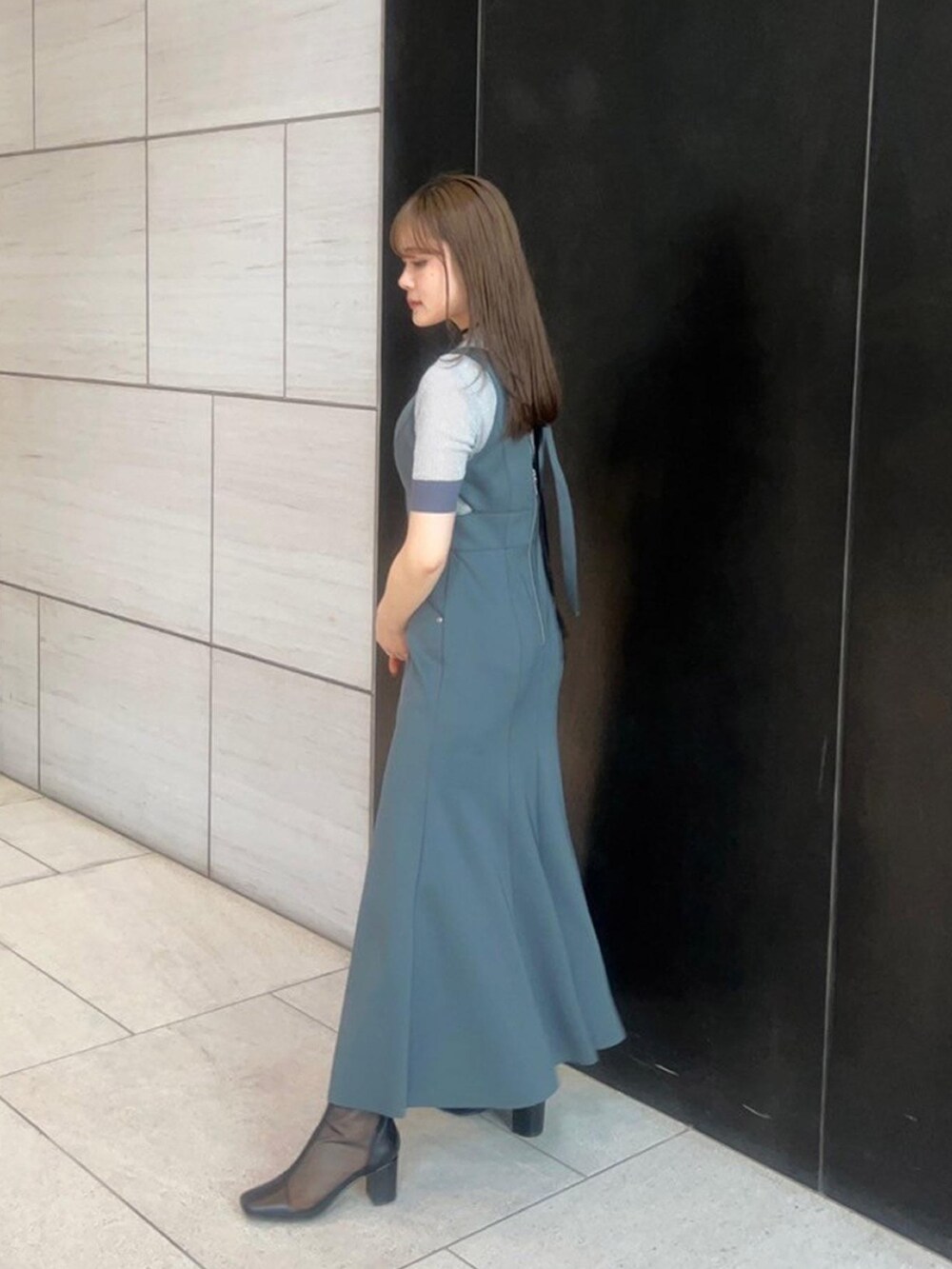 シルバー系のニット/セーター、グレー系のジャンパースカートを着用したレディースの春コーディネートの2枚目の写真