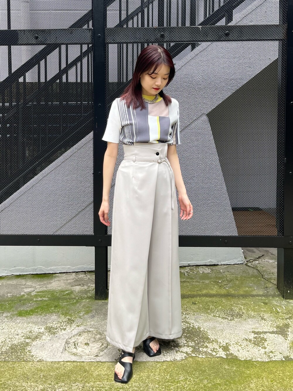 イエロー系のニット/セーター、グレー系のスラックスを着用したレディースの春コーディネートの2枚目の写真