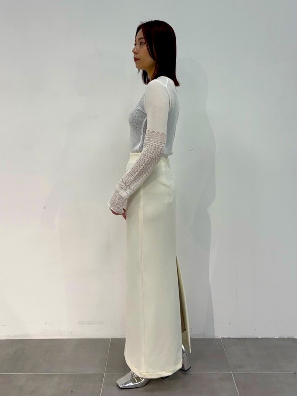 ホワイト系のニット/セーター、ホワイト系のスカートを着用したレディースの春コーディネートの2枚目の写真