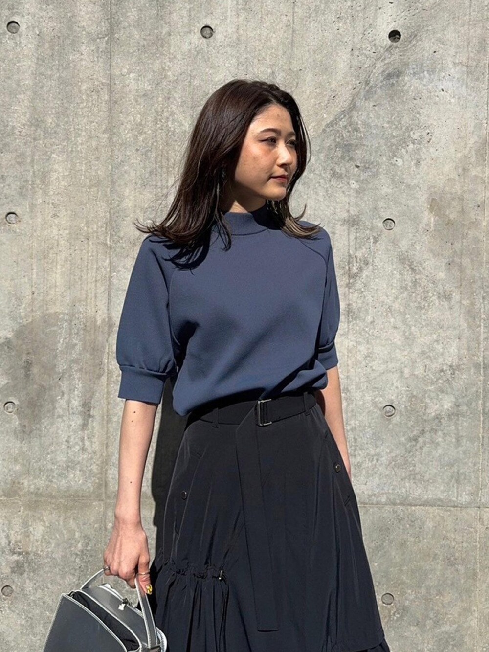 グレー系のニット/セーター、ブラック系のスカートを着用したレディースの春コーディネートの4枚目の写真