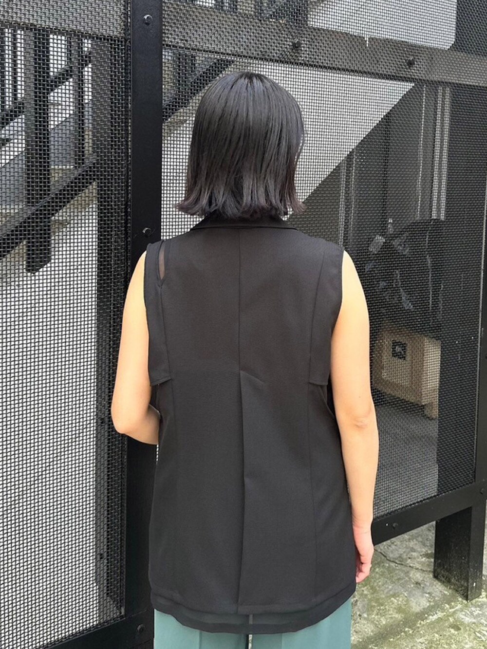 ブラック系のベスト、グリーン系のスラックスを着用したレディースの春コーディネートの6枚目の写真