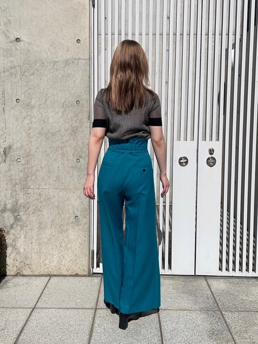 ゴールド系のニット/セーター、グリーン系のスラックスを着用したレディースの春コーディネートの3枚目の写真