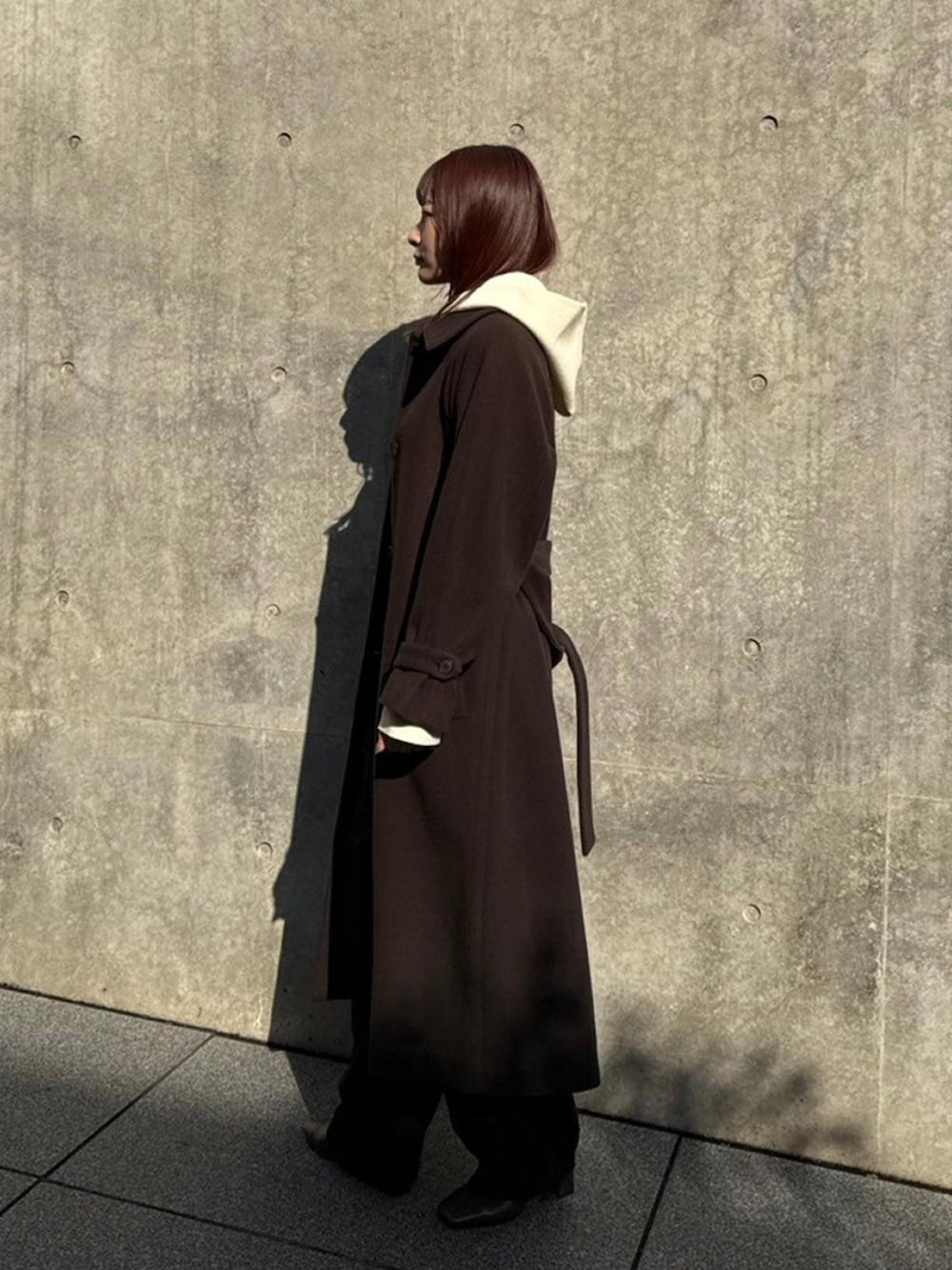 ブラウン系のステンカラーコートを着用したレディースの秋コーディネートの2枚目の写真