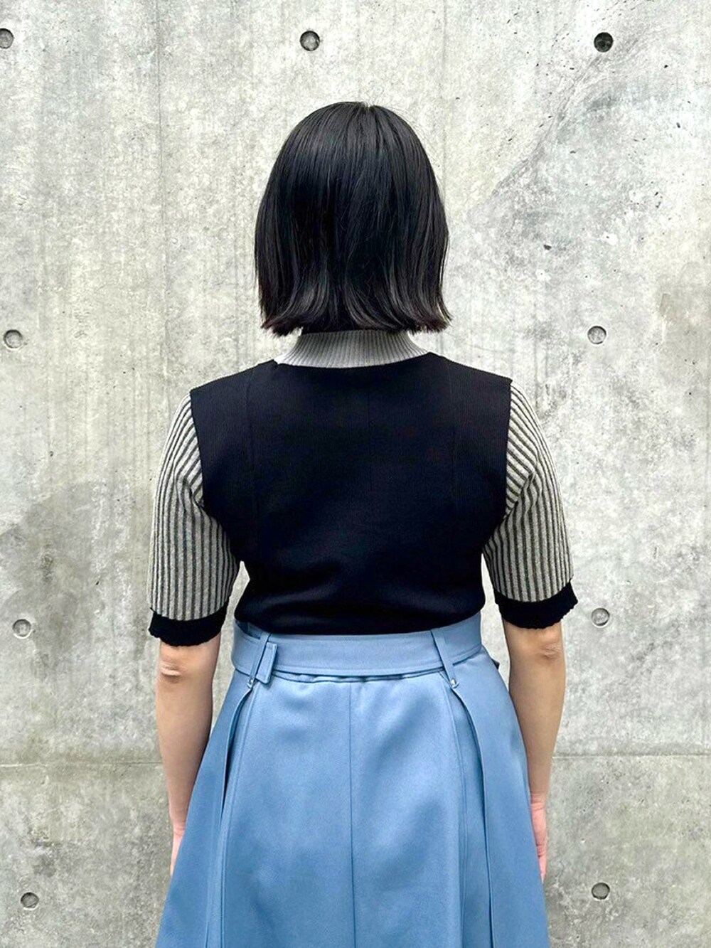 ブラック系のニット/セーター、ブルー系のスカートを着用したレディースの春コーディネートの6枚目の写真