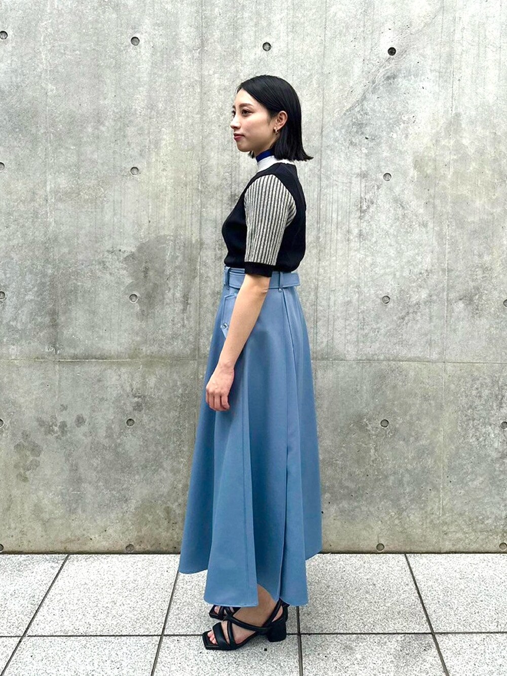 ブラック系のニット/セーター、ブルー系のスカートを着用したレディースの春コーディネートの2枚目の写真