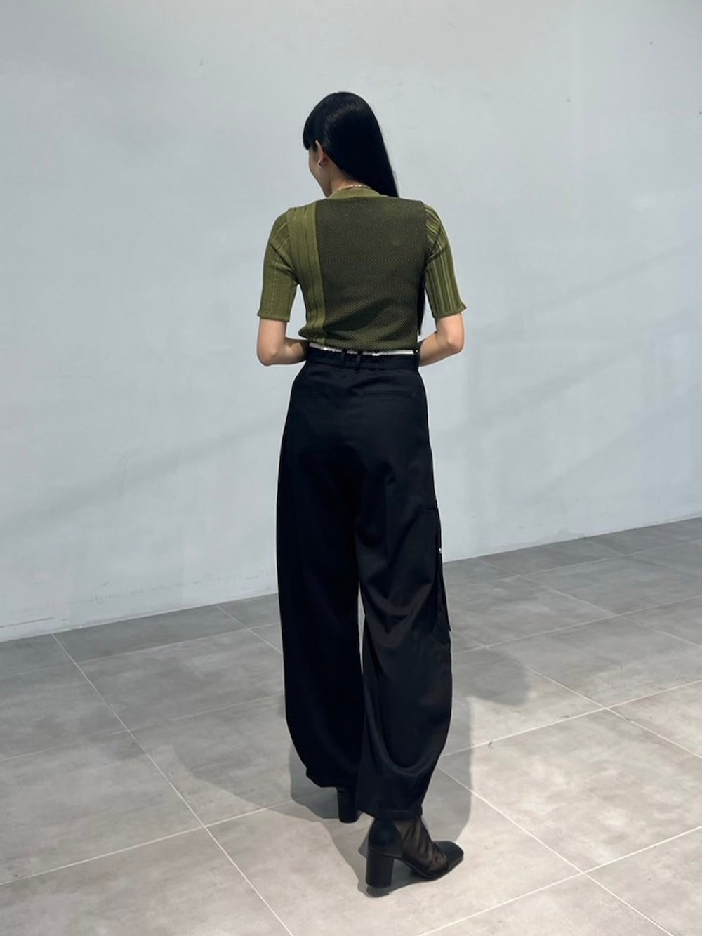 グリーン系のニット/セーター、ブラック系のその他パンツを着用したレディースの秋コーディネートの3枚目の写真