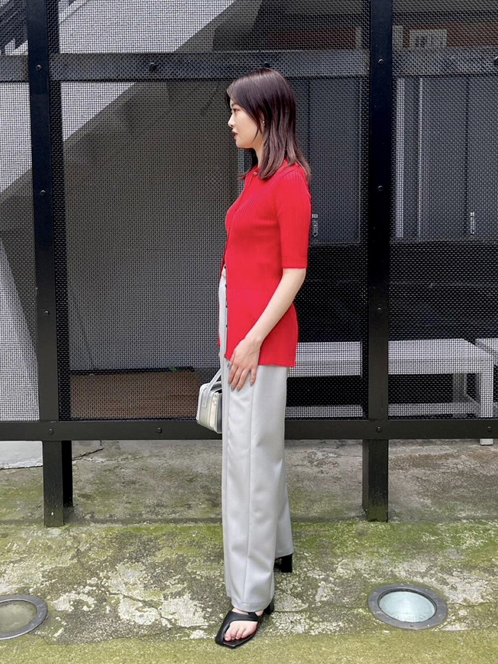 グレー系のその他パンツ、レッド系のニット/セーターを着用したレディースの春コーディネートの2枚目の写真