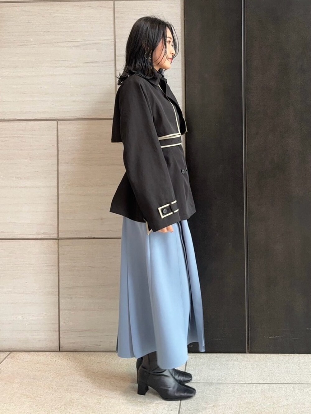 ブラック系のトレンチコートを着用したレディースの春コーディネートの2枚目の写真