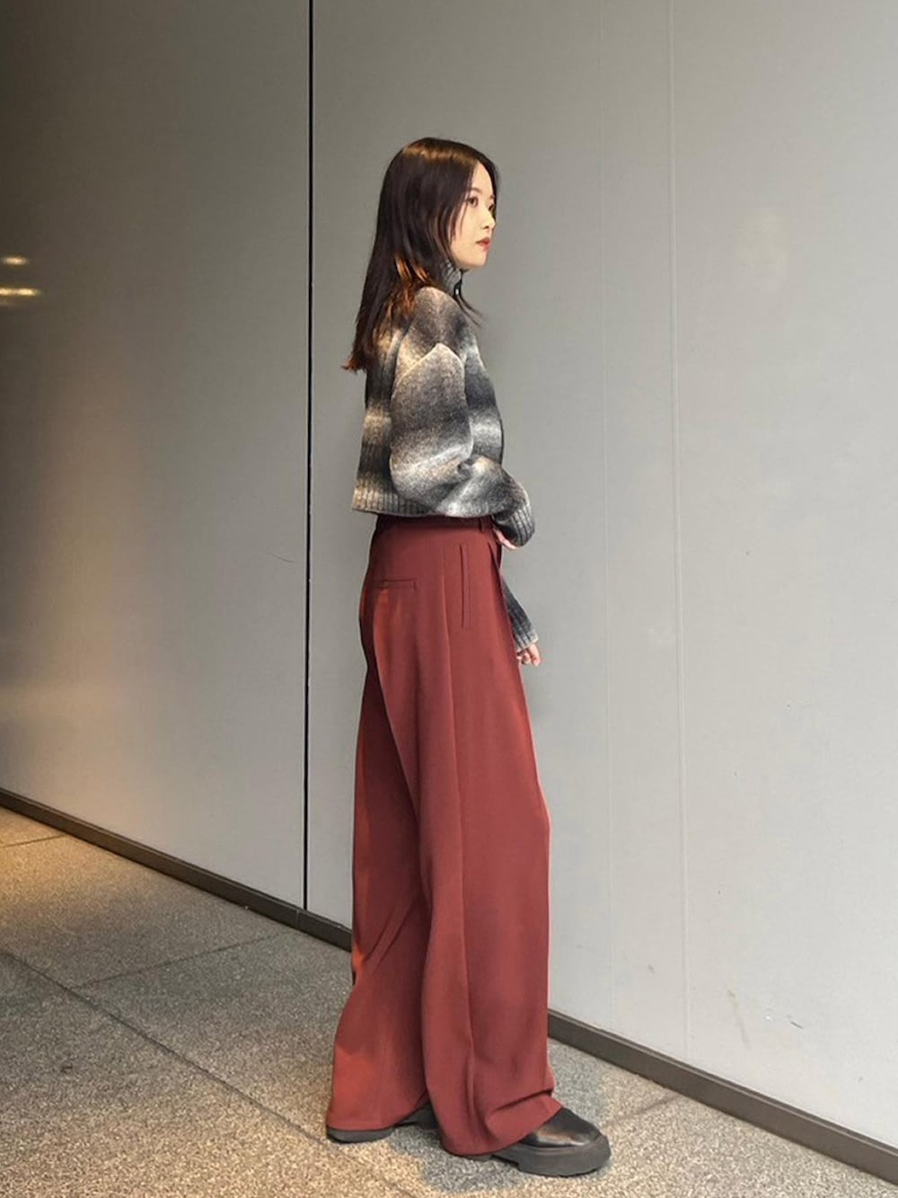 ブラック系のニット/セーター、レッド系のスラックスを着用したレディースの秋コーディネートの3枚目の写真