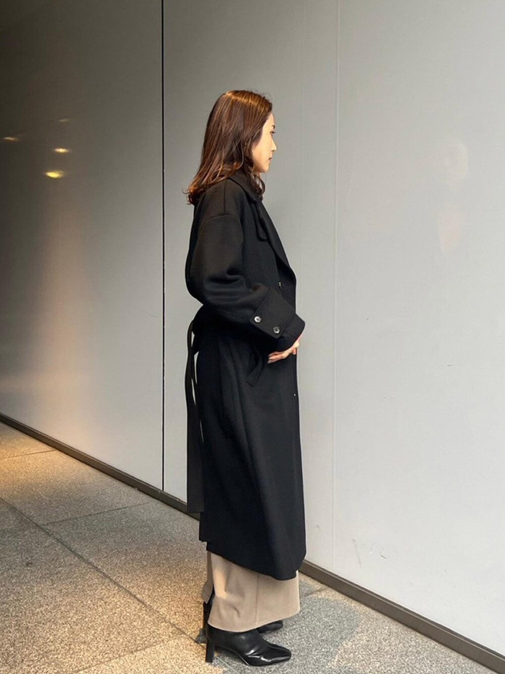 ブラック系のステンカラーコートを着用したレディースの秋コーディネートの2枚目の写真