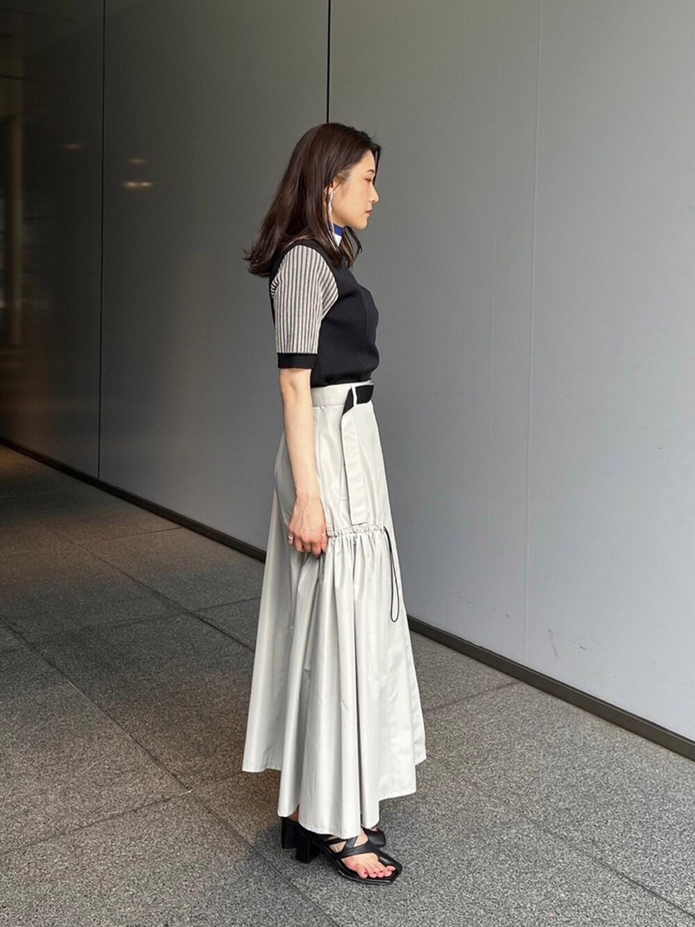 ブラック系のニット/セーター、ベージュ系のスカートを着用したレディースの夏コーディネートの2枚目の写真