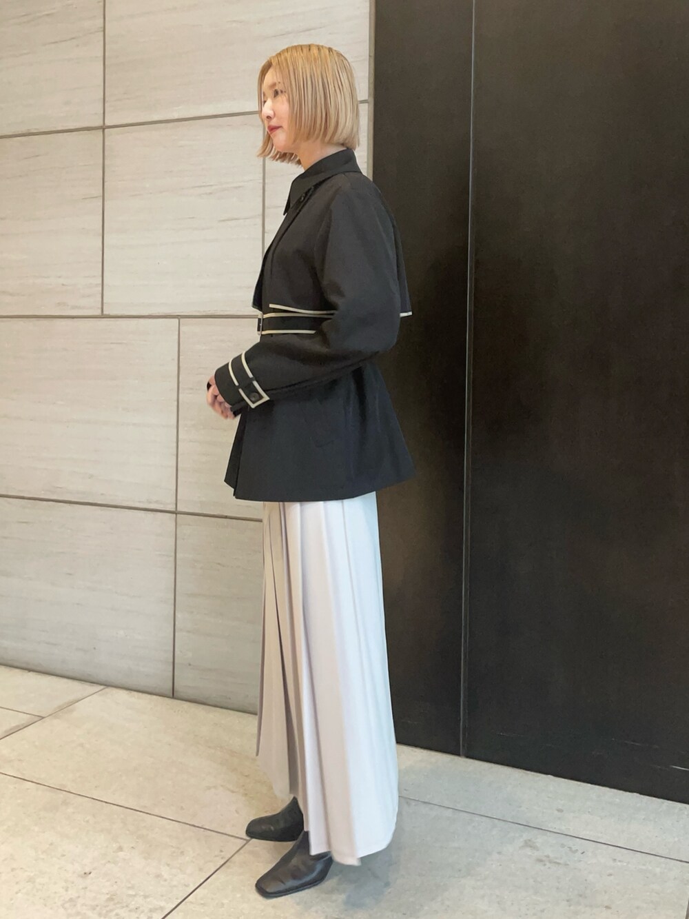 ブラック系のトレンチコートを着用したレディースの春コーディネートの2枚目の写真