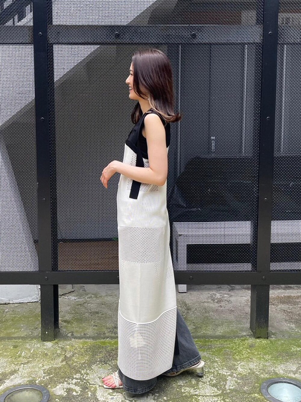 ホワイト系のワンピース、ブラック系のタンクトップ、ブラック系のデニムパンツを着用したレディースの春コーディネートの4枚目の写真